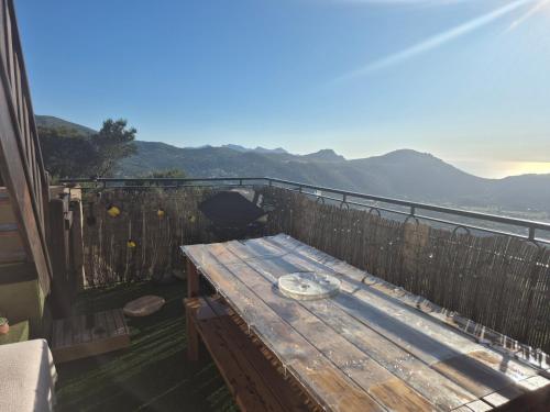 a wooden table on a balcony with a view of the mountains at Superbe Maison de village authentique vue mer in SantʼAntonino