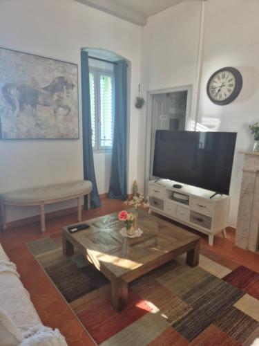 a living room with a television and a coffee table at Superbe Maison de village authentique vue mer in SantʼAntonino