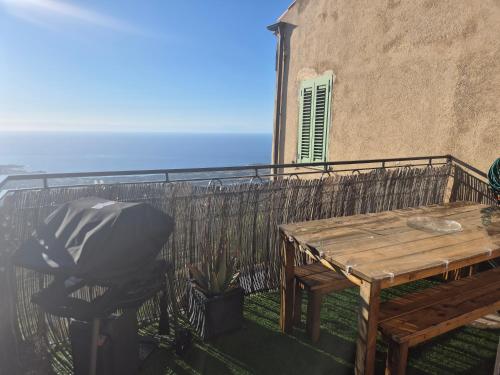 a balcony with a wooden table and a fence at Superbe Maison de village authentique vue mer in SantʼAntonino