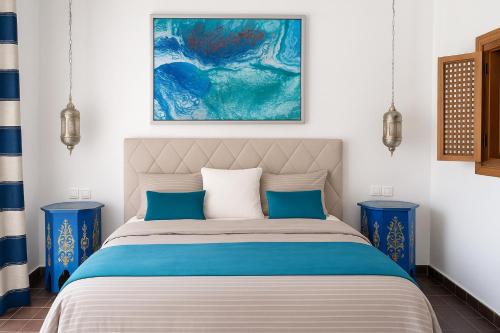 a bedroom with a bed and two blue end tables at Riad Maison de ville piscine privée in El Jadida