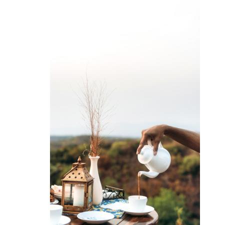 a person pouring a cup of tea on a table at Jungle Ghar in Pachmarhī