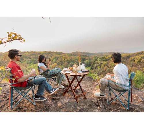 three people sitting at a table on top of a hill at Jungle Ghar in Pachmarhī
