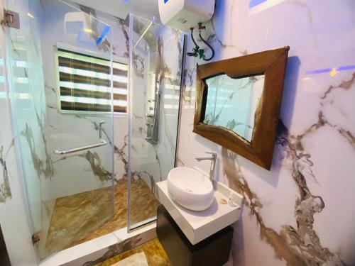 a bathroom with a shower and a sink and a mirror at Presken Hotel @Oniru in Lagos
