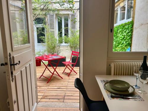 Une porte ouverte s'ouvre sur une terrasse avec une table et des chaises. dans l'établissement Le Patio des Ducs, Hypercentre, à Dijon