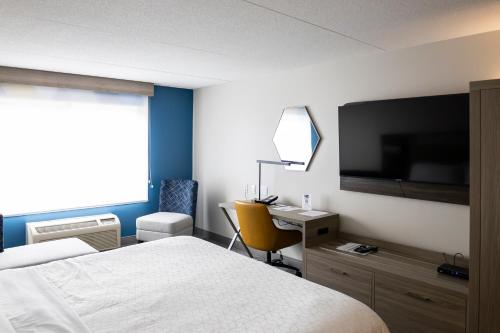a bedroom with a bed and a desk and a television at Holiday Inn Express Hotel & Suites Brockville by IHG in Brockville