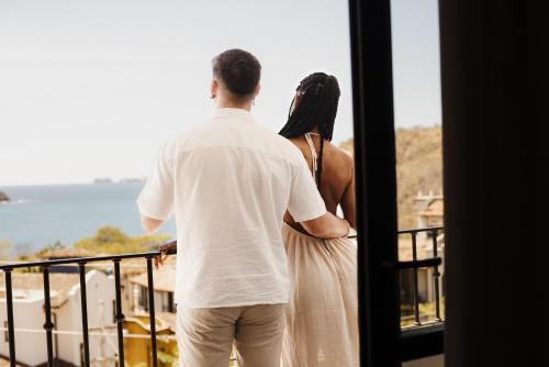 a man and a woman looking out of a window at El Prado: New 2br Condo in Las Catalinas in Playa Danta