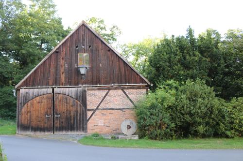 a large wooden barn with a large door at Landhotel Kahrmühle in Pressath