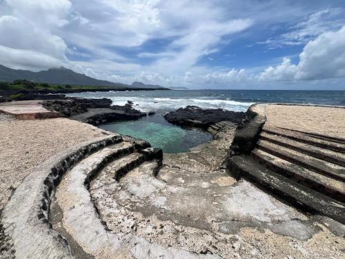 a bench sitting on the beach next to the ocean at Maliu Mai Beach Resort in Tafuna