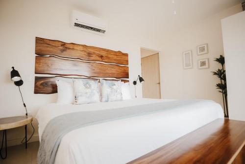 a bedroom with a large white bed with a wooden headboard at El Prado: New 2br Condo in Las Catalinas in Playa Danta