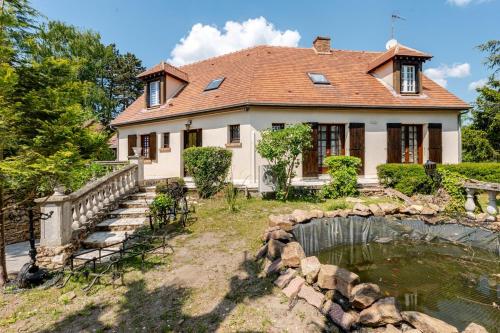 a house with a pond in front of it at Magnifique villa au cœur de la nature in Marigny-en-Orxois