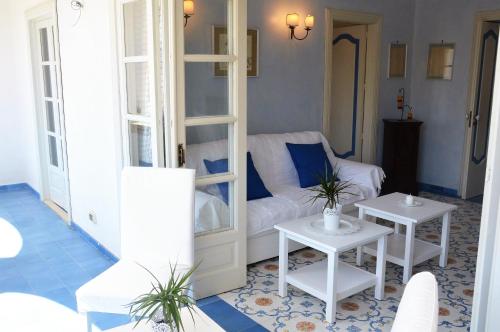 sala de estar con sofá blanco y 2 mesas en L'Atelier del Pittore Apartment, en Taormina