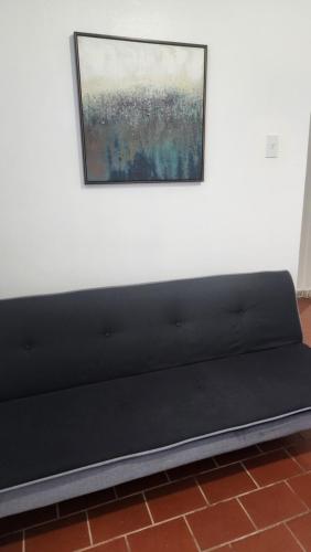 a black couch against a white wall with a painting at Sweet Sunset II- Rompeolas Beach in Aguadilla