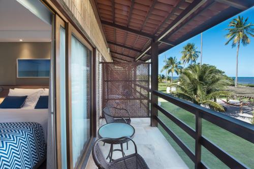 a balcony with a bed and a table and chairs at Salinas Maragogi All Inclusive Resort in Maragogi