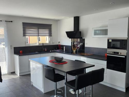 une cuisine avec une table noire et des chaises noires dans l'établissement La Villa les Terrasses du Canal, à Capestang