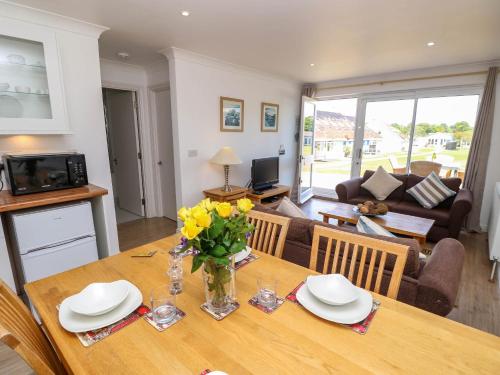 a dining room table with a vase of flowers on it at Cape 12, in Yarmouth
