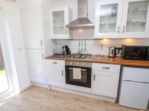 a kitchen with white cabinets and a stove top oven at Cape 12, in Yarmouth