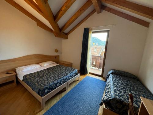 a bedroom with two beds and a window at Hotel Caminetto - Rooms and Apartments in Cembra