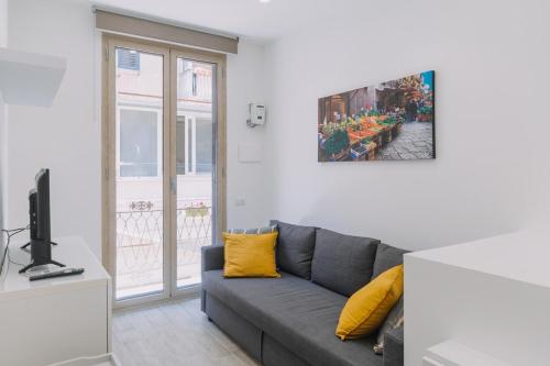 a living room with a gray couch and a window at Serenello Home in Palermo