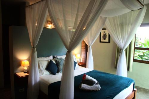 a bedroom with a canopy bed with a stuffed animal on it at Chill Mango in Paracuru