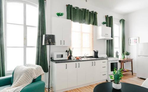 a kitchen with white cabinets and green curtains at Lofts du Presbytère in Matane