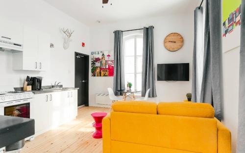 a living room with a yellow couch and a kitchen at Lofts du Presbytère in Matane