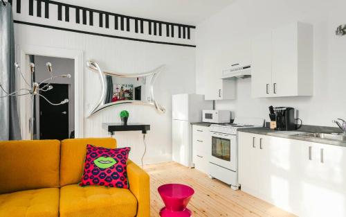 a living room with a yellow couch and a kitchen at Lofts du Presbytère in Matane