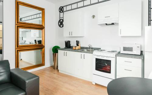 a kitchen with white cabinets and a sink and a mirror at Lofts du Presbytère in Matane