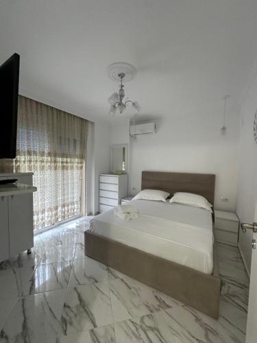 una camera da letto con un grande letto e una televisione di Liam'S Apartment a Sarandë
