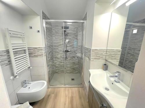 a white bathroom with a shower and a sink at La Casa di Ines in San Gimignano