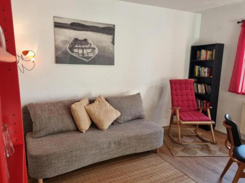 a living room with a couch and a red chair at Alpaka Ferienhof Lübsee in Lübsee