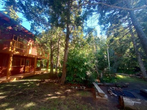 a house with a tree in the middle of a yard at Cabaña Nido del Bosque in San Carlos de Bariloche