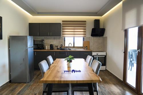 a kitchen with a wooden table with chairs and a refrigerator at Blue Horizon in Sevastí
