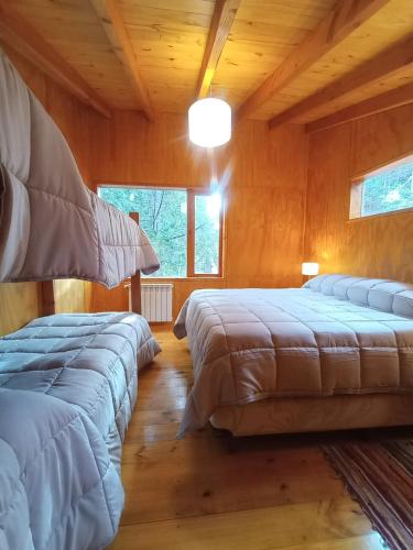 three beds in a room with wooden walls at Cabaña Nido del Bosque in San Carlos de Bariloche