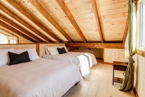 two beds in a room with wooden ceilings at OTIS Nature in Lamarche