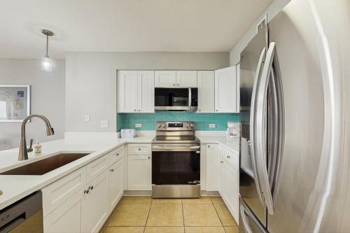 a kitchen with white cabinets and a stainless steel refrigerator at Tilghman Beach and Golf 1519 in North Myrtle Beach