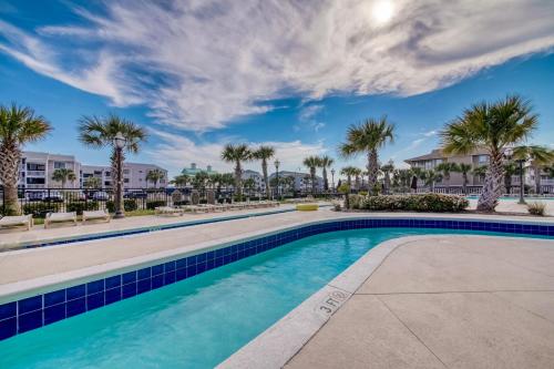 a swimming pool with palm trees and buildings at Tilghman Beach and Golf 1519 in North Myrtle Beach