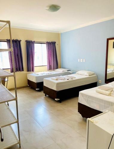 a room with three beds and a ladder in it at Pousada do Toby in Canoa Quebrada