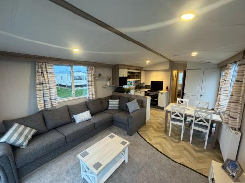 a living room with a couch and a table at Fantasy Island - Eastgate F6 - The Ardennes with Hot Tub - Coastal Caravan Breaks in Ingoldmells