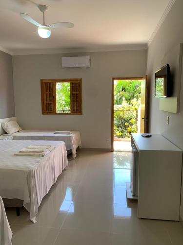 a bedroom with two beds and a door to a yard at Pousada Faruk in Olímpia