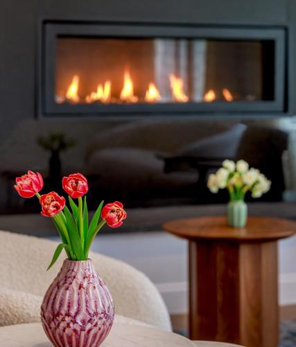 a pink vase with flowers on a table in front of a fireplace at The Brunswick Hotel in Brunswick
