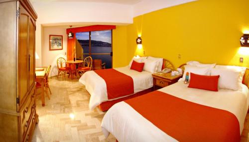 a hotel room with two beds and a table at Copacabana Beach Hotel Acapulco in Acapulco