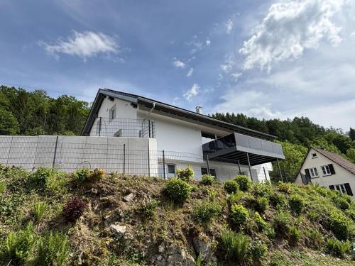 a white house on a hill with trees in the background at Waldklang Panorama in Alpirsbach