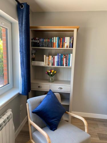 a chair with a blue pillow in front of a book shelf at Stagstone apartment in Fortrose in Fortrose