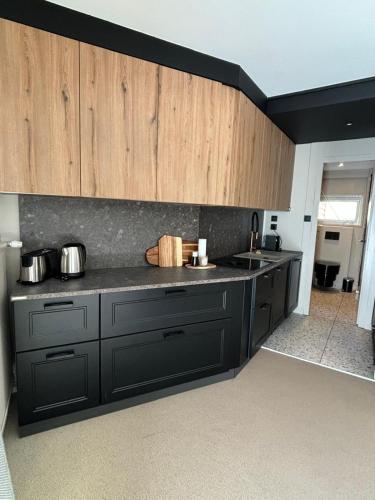 une cuisine avec des comptoirs noirs et des armoires en bois dans l'établissement L'Appartement La Mongie, à Bagnères-de-Bigorre