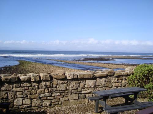 a wooden picnic table sitting next to a stone wall at Sea View in Balnacart