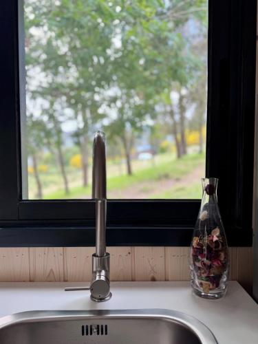 a sink with a vase of flowers next to a window at Casa d' Além Turismo e Natureza - Refúgio do Bosque in Torneiro