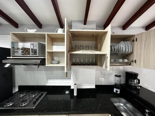 a kitchen with white cabinets and a black counter top at Apartamento cerca al metro y viva envigado in Itagüí