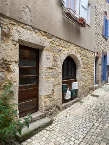 - un bâtiment en pierre avec une porte et une rue dans l'établissement T2 la Canourgue, à La Canourgue