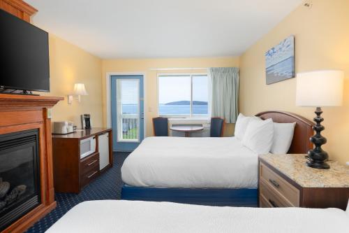 a hotel room with two beds and a fireplace at Fireside Inn, Ocean's Edge in Belfast
