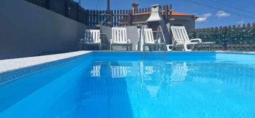 a group of white chairs sitting next to a swimming pool at Superb Bruzende Village in Baião